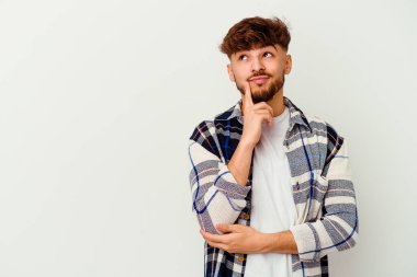 Beyaz arka planda izole edilmiş genç Faslı şüpheli ve şüpheci bir ifadeyle yana bakıyor..