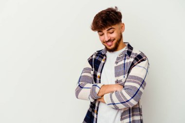 Beyaz arka planda izole edilmiş genç Faslı adam kollarını kavuşturarak gülümsüyor..