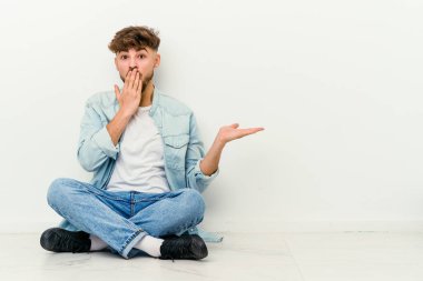 Beyaz arka planda izole bir şekilde yerde oturan Faslı genç adam, avuç içi fotokopi alanını tutmaktan çok etkilendi..