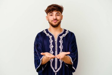 Beyaz arka planda izole edilmiş genç Faslı bir adam elinde avuç içi bir şeyle kameraya sunuyor..