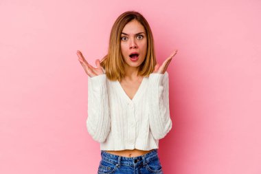 Pembe arka planda izole edilmiş genç beyaz kadın şaşırmış ve şok olmuş..