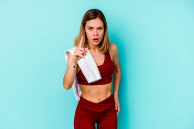 Genç beyaz kadın, mavi arka planda izole edilmiş. Bir fikri var, ilham verici bir kavram..