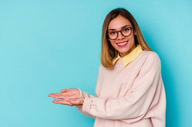 Mavi arka planda izole edilmiş beyaz bir kadın. Elinde palmiye ağacının üzerinde bir kopya alanı var..