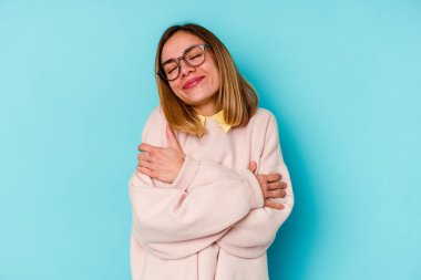 Genç beyaz kadın, mavi arka planda izole edilmiş gülümseyen kaygısız ve mutlu..