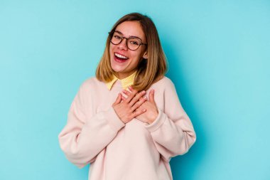 Mavi arka planda izole edilmiş genç beyaz kadın avuçlarını göğsüne bastıran dostça bir ifadeye sahip. Aşk konsepti.