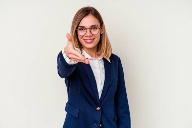 Beyaz arka planda izole edilmiş beyaz tenli genç bir kadın selamlaşma jesti olarak kameraya elini uzatıyor..