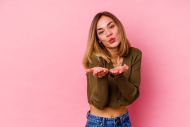 Beyaz bir kadın pembe arka planda izole edilmiş dudaklar kıvrılmış ve hava öpücüğü göndermek için avuç içleri tutulmuş..