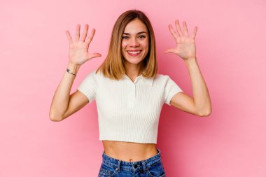 Pembe arka planda izole edilmiş genç beyaz kadın on numarayı elleriyle gösteriyor..
