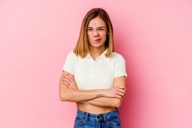 Pembe arka planda izole edilmiş genç beyaz kadın alaycı bir ifadeyle kameraya bakıyor..