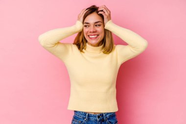 Pembe arka planda soyutlanmış beyaz bir kadın ellerini başının üstünde tutarak neşe içinde gülüyor. Mutluluk kavramı.