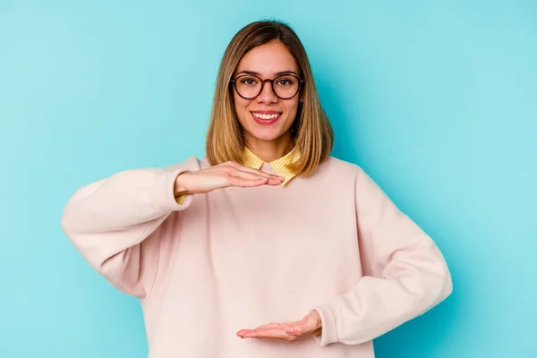 Giovane Studentessa Caucasica Isolato Sfondo Blu Tenendo Qualcosa Con Entrambe — Foto Stock