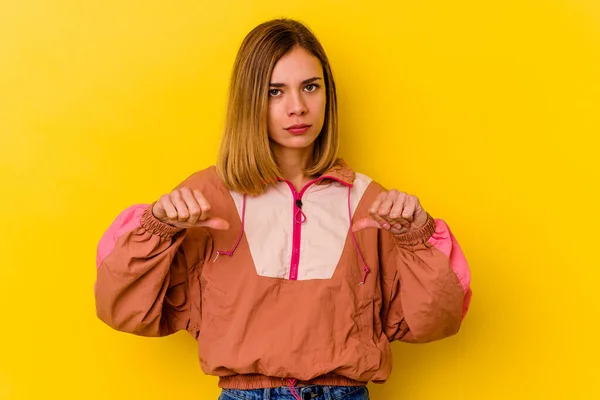 Young caucasian skinny woman isolated on yellow background showing a dislike gesture, thumbs down. Disagreement concept.