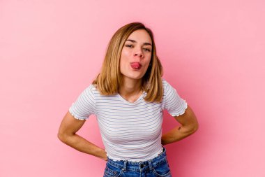 Pembe arka planda izole edilmiş beyaz bir kadın. Komik ve dost canlısı bir dil uzatıyor..