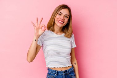 Genç beyaz kadın pembe arka planda izole edilmiş neşeli ve kendinden emin, iyi bir jest yapıyor..