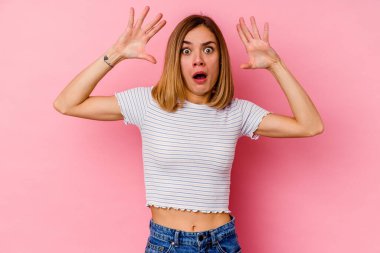 Pembe arka planda izole genç beyaz kadın zaferi ya da başarıyı kutluyor, şaşırıyor ve şok oluyor..