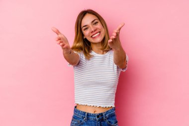 Pembe arka planda izole edilmiş genç beyaz kadın kameraya sarıldığı için kendinden emin..