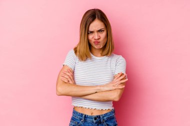 Pembe arka planda izole edilmiş genç beyaz kadın yanakları patlatıyor, yorgun bir ifade takınıyor. Yüz ifadesi kavramı.