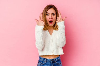 Pembe arka planda izole edilmiş beyaz bir kadın ağzı açık bir şekilde üst tarafı işaret ediyor..