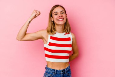 Pembe arka planda soyutlanmış, tasasız ve heyecanlı genç bir beyaz kadın. Zafer konsepti.