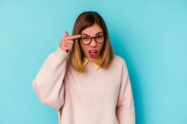 Mavi arka planda izole edilmiş genç beyaz kadın işaret parmağıyla hayal kırıklığı jesti gösteriyor..