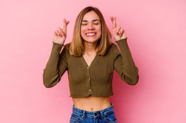 Pembe arka planda izole edilmiş beyaz bir kadın şans getirsin diye dua ediyor.