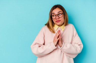 Kafkas kökenli genç bir kadın mavi arka planda izole edilmiş, bir plan hazırlıyor..