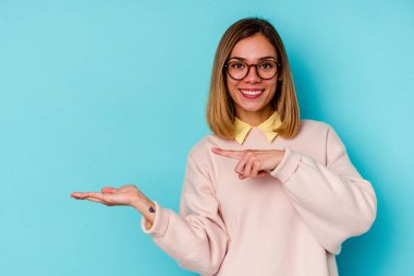 Mavi arka planda izole edilmiş beyaz bir kadın. Elinde palmiye ağacının bir kopyası olduğu için heyecanlı..