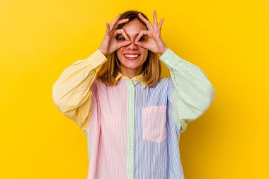 Sarı arka planda izole edilmiş beyaz tenli genç bir kadın gözlerinde sorun olmadığını gösteriyor.