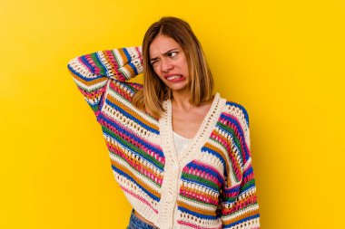 Sarı arka planda izole edilmiş, genç beyaz kadın yorgun ve uykulu, elini başının üstünde tutuyor..