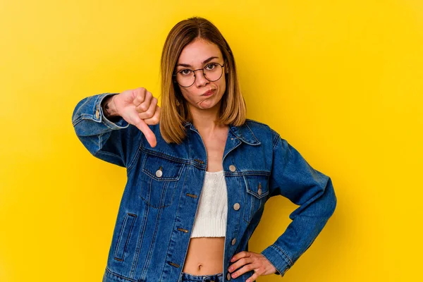 Young caucasian skinny woman isolated on yellow background showing thumb down, disappointment concept.