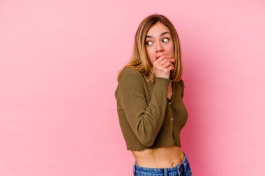 Pembe arka planda izole edilmiş beyaz bir kadın. Düşünceli bir şekilde ağzıyla ağzını kapatan bir fotokopi odasına bakıyor..