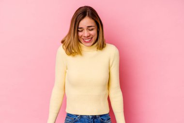 Pembe arka planda izole edilmiş genç beyaz kadın gülüyor ve gözlerini kapıyor, rahatlamış ve mutlu hissediyor..