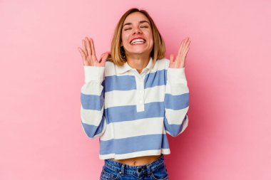 Pembe arka planda soyutlanmış beyaz bir kadın yüksek sesle gülüyor ve elini göğsüne koyuyor..