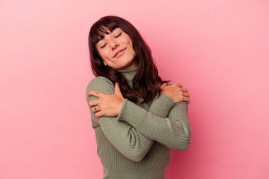 Pembe arka planda soyutlanmış beyaz bir kadın. Kucaklaşma, kaygısız gülümseme ve mutluluk..