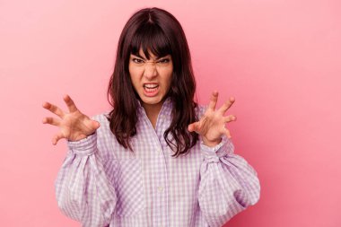 Pembe arka planda izole edilmiş genç beyaz kadın pençelerini kedi taklidi yaparken gösteriyor, agresif bir hareket..