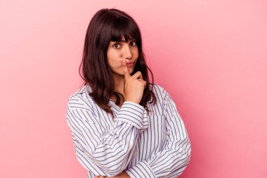 Pembe arka planda izole edilmiş genç beyaz kadın alaycı bir ifadeyle kameraya bakıyor..