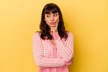 Kafkasyalı genç bir kadın, sarı arka planda izole edilmiş. Bir strateji planlıyor, bir işin nasıl olacağını düşünüyor..