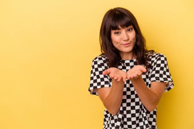 Sarı arka planda izole edilmiş genç, beyaz bir kadın. Dudaklarını kıvırıyor, avuç içlerini tutuyor ve hava öpücüğü yolluyor..