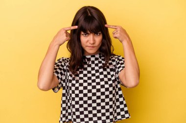 Sarı arka planda izole edilmiş genç beyaz kadın bir göreve odaklanmış, işaret parmaklarını işaret ediyor..