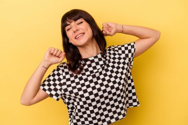 Sarı arka planda izole edilmiş, kollarını uzatan, rahat bir pozisyonda genç beyaz bir kadın..