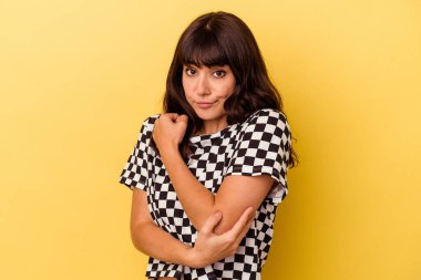 Sarı arka planda izole edilmiş genç beyaz kadın kafası karışmış, kuşkulu ve kendinden emin değil..