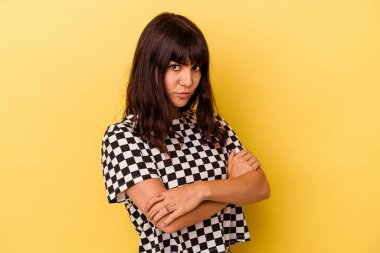 Sarı arka planda izole edilmiş, hoşnutsuzca kaşlarını çatmış, kollarını kavuşturmuş genç beyaz bir kadın..