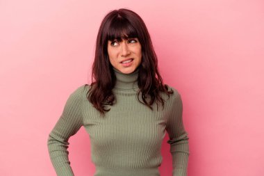 Pembe arka planda izole edilmiş genç beyaz kadın kafası karışmış, kuşkulu ve güvensiz hissediyor..