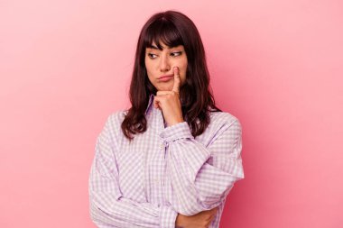 Pembe arka planda izole edilmiş genç beyaz kadın bir strateji planlıyor, bir iş kurmanın yollarını düşünüyor..