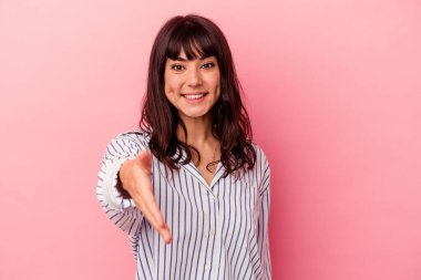 Pembe arka planda izole edilmiş beyaz bir kadın. Kameraya elini uzatıp selam veriyor..