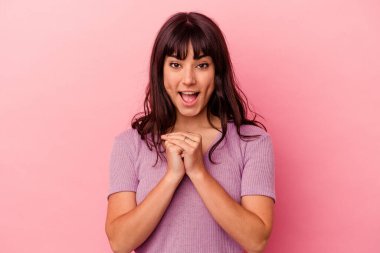 Pembe arka planda izole edilmiş genç beyaz bir kadın şans için dua ediyor, hayrete düşüyor ve ağzını açıp önüne bakıyor..