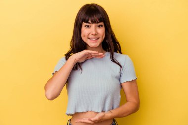 Sarı arka planda izole edilmiş beyaz bir kadın iki eliyle bir şey tutuyor..