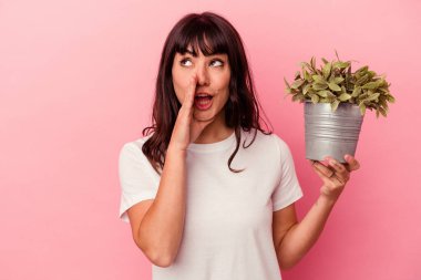 Pembe arka planda izole edilmiş bir bitkiyi elinde tutan beyaz bir kadın gizli bir fren haberinin olduğunu söylüyor.