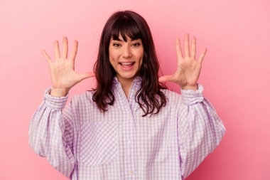 Pembe arka planda izole edilmiş genç beyaz kadın on numarayı elleriyle gösteriyor..