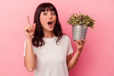 Pembe arka planda bir bitki tutan beyaz bir kadının bir fikri var, ilham verici bir kavram..